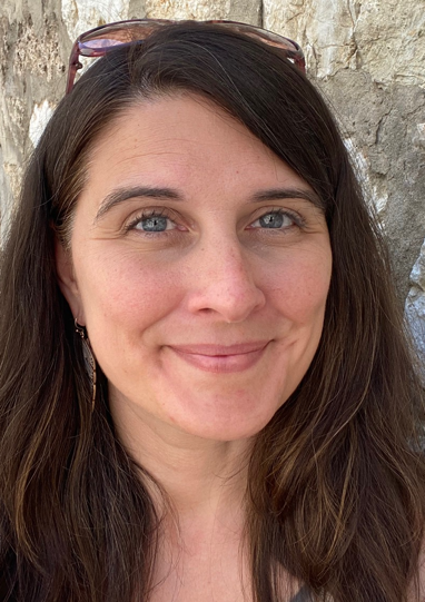 A headshot of Rebecca. She has long brown hair,
                blue eyes, and is smiling.